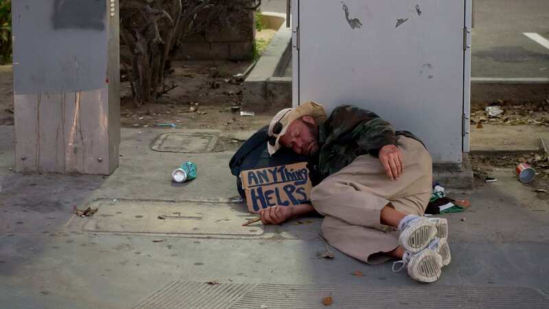 Homeless man with cardboard sign sleeping on the sidewalk in front of a 7-Eleven in Pacific Beach, California (Image: ullstein bild via Getty Images)