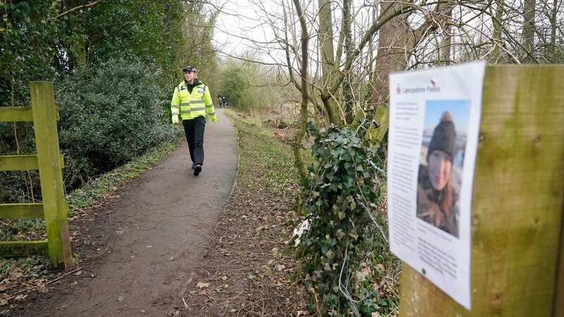 A police community support officer walks towards a police appeal poster in St Michael