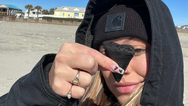 Leah with her exciting discovery which is believed to come from a great white shark (Image: Jam Press/Leah McLamb)