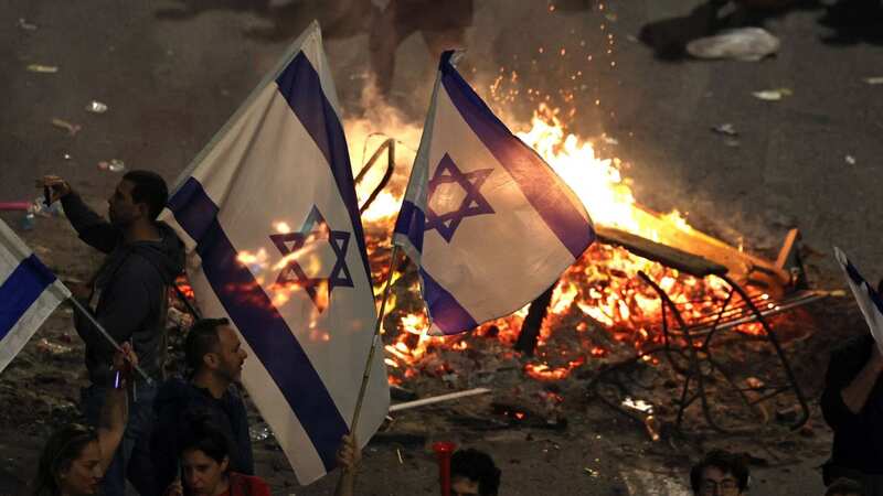 Protesters block a road and hold national flags as they clash with the police during a rally against the Israeli government (Image: AFP via Getty Images)