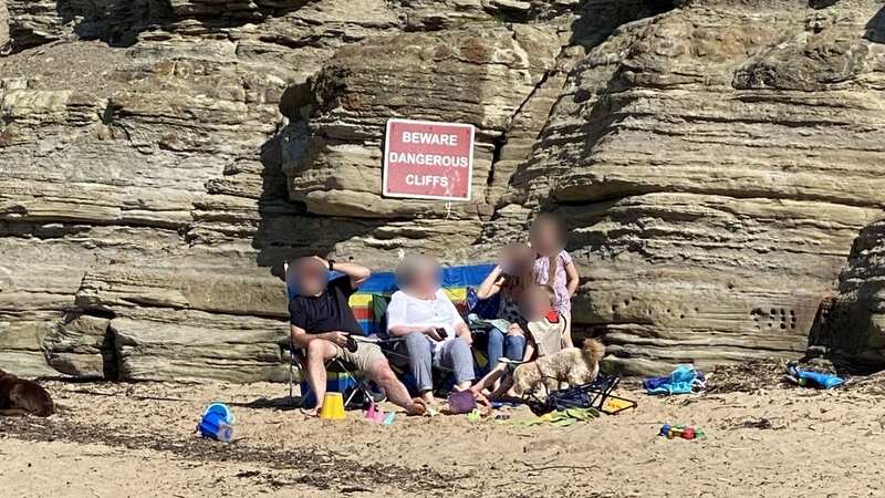 The family were pictured sat underneath the cliff next to a 