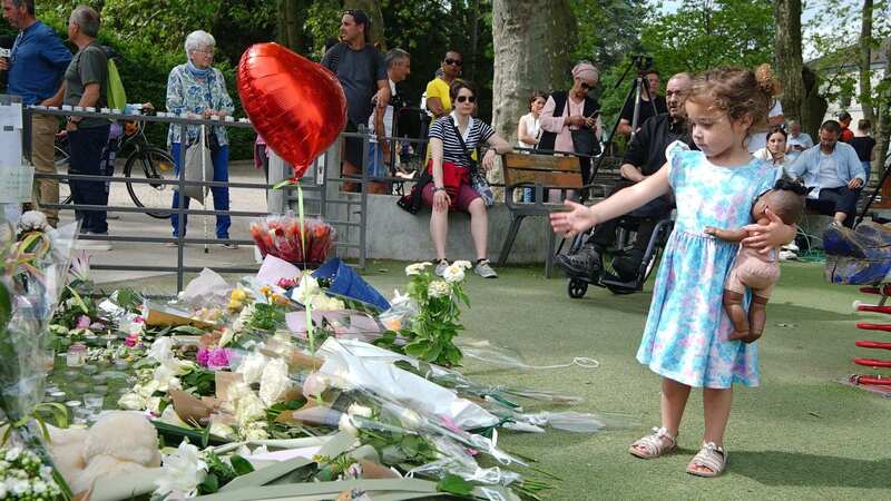 A little girl lays tributes near the scene at a lakeside playground in Annecy, France (Image: PA)