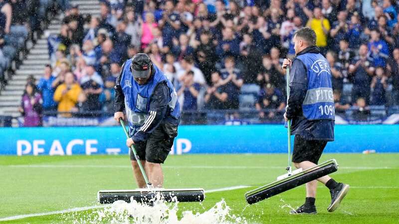 Ground staff try to clear water off the Hampden pitch (Image: Stuart Wallace/REX/Shutterstock)