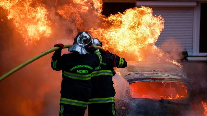 Firefighters put out a burning car during protests in Lille (Image: AFP via Getty Images)