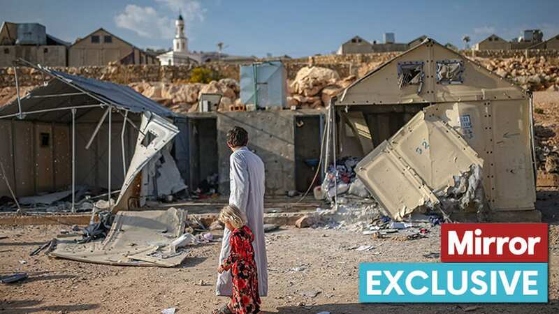A child and father walk past devastation after a cluster bomb attack (Image: Anadolu Agency via Getty Images)