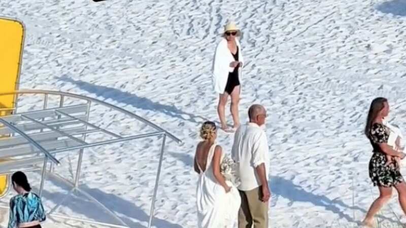 The woman turns back as the bride appears to make a comment after the beachgoer walked in front of her (Image: coryatrandom/TikTok)