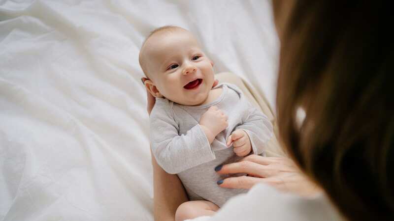 A mother holds her smiling newborn baby (file image) (Image: Getty Images)
