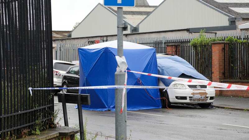 This image shows the burnt-out van under a blue tarp in Burton-upon-Trent (Image: SWNS)