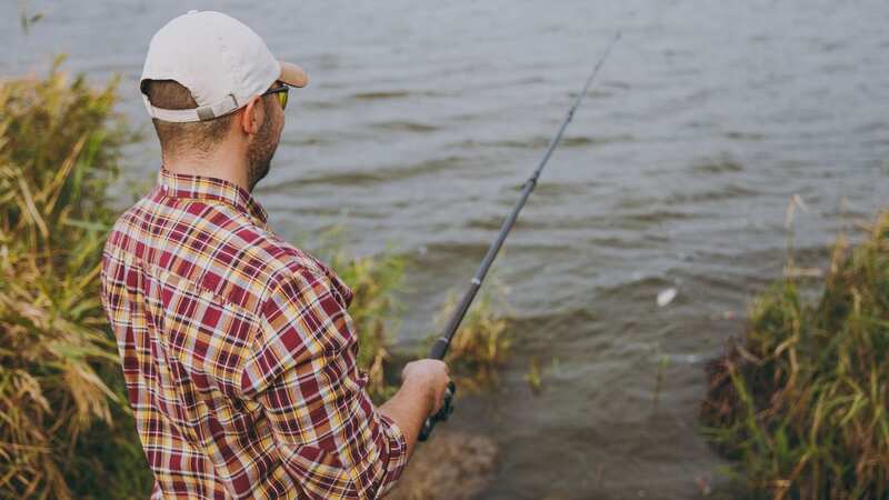 A young man enjoys a spot of fishing at a lake (Image: Getty Images/iStockphoto)