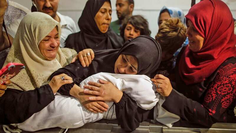 A mother holds her baby at the morgue (Image: AFP/Getty Images)