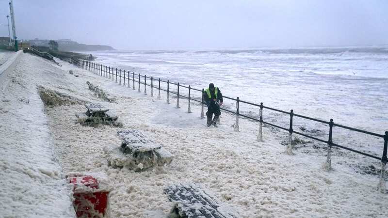A man walks through sea foam in Seaburn, Sunderland, as Storm Babet batters the UK (Image: PA)