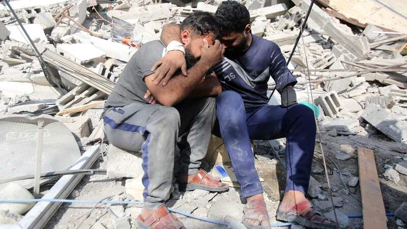 Palestinians mourn as they sit on the rubble of a building in Gaza City