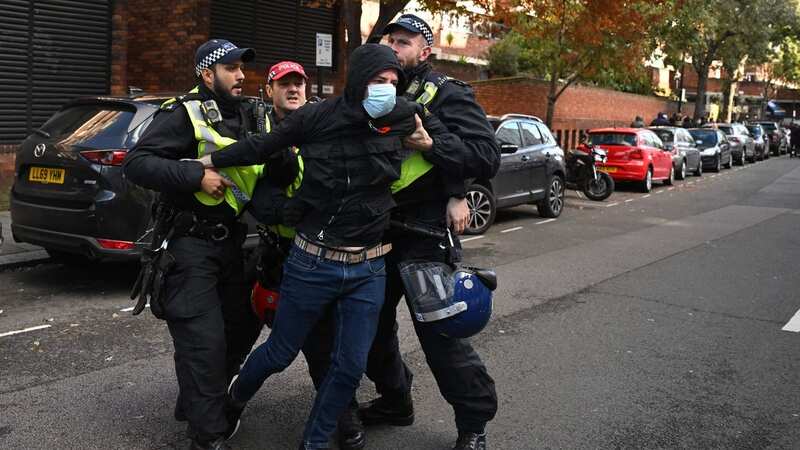 Police officers detain a man in the street close to the 