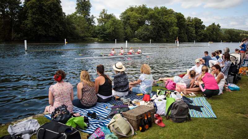 Spectators look on as competitors race along the River Thames during the Henley Women