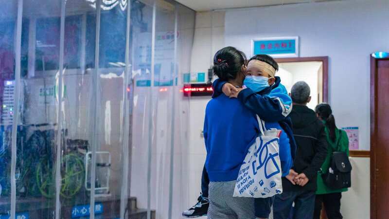 A mum is pictured in a Chinese hospital, holding her child who has respiratory symptoms (Image: NurPhoto via Getty Images)