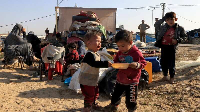 Displaced Palestinians who fled from Khan Yunis sit with their belongings outside makeshift shelters (Image: AFP via Getty Images)