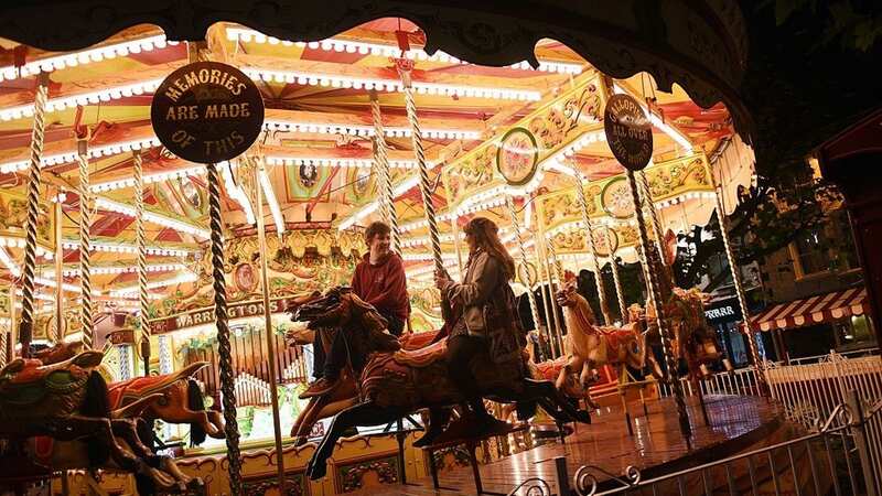 Members of the public ride a carousel adjacent to the 