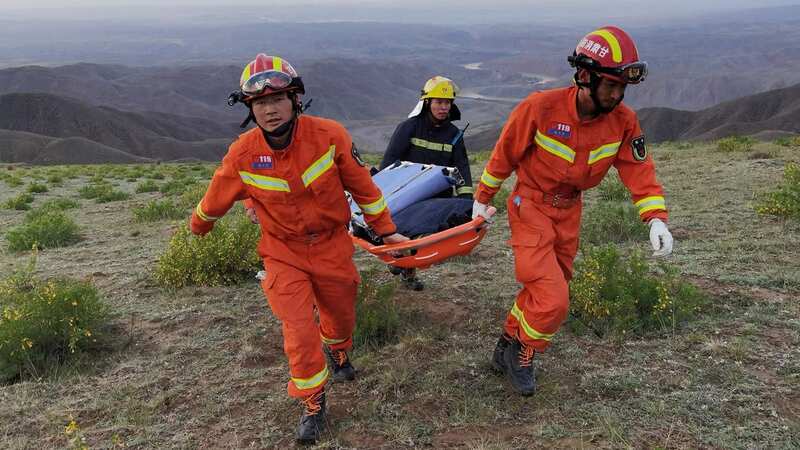 Rescue workers carry equipment while searchng for runners who competed in a cross-country mountain race during a storm (Image: AFP via Getty Images)
