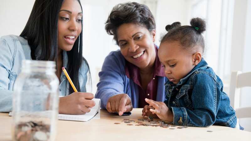 Family gathered round the table counting coins (Image: Getty Images/Tetra images RF)