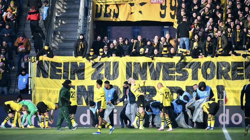 Players helped to clear the pitch after fans protested with chocolate coins (Image: Getty Images)