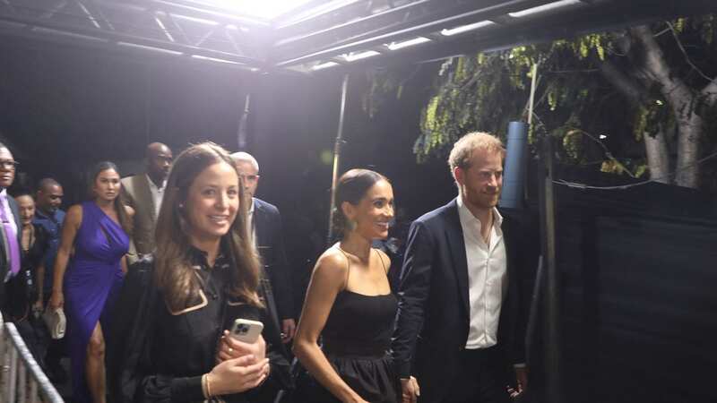 Prince Harry and Meghan Markle hold hands on the red carpet at the premiere of 