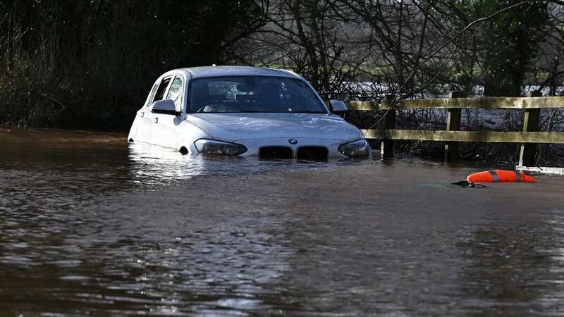 Floodwater surrounds a car abandoned by the side of a road last month after downpours (Image: AFP via Getty Images)