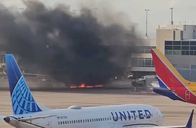 A frame from a video shows flames under a plane and black smoke rising at the Denver airport. Courtesy Joshua Sunberg