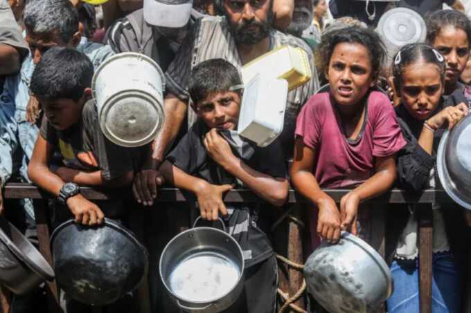 Palestinians, including children, who are struggling to access food due to Israel’s blockade and ongoing attacks on the Gaza Strip, wait in line to receive hot meals (Picture: Getty)