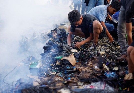 Men squatting down to sift through charred remains in Gaza dqxikeidqkikdinv