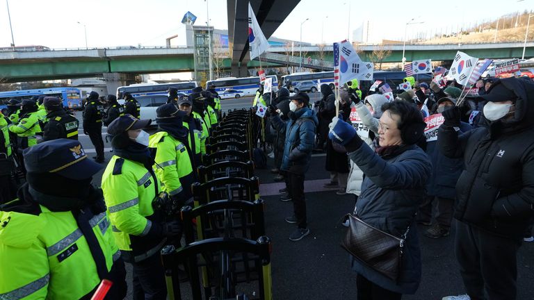 Supporters of impeached South Korean President Yoon Suk Yeol stage a rally to oppose a court having issued a warrant to detain Yoon, as police offices stand guard near the presidential residence in Seoul, South Korea, Friday, Jan. 3, 2025. The letters read "Oppose Impeachment." (AP Photo/Lee Jin-man) dqxikeidqkikdinv