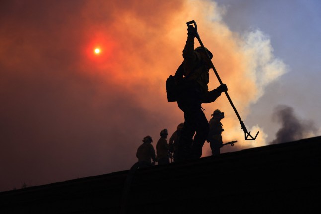Firefighters work as a brush fire burns in Pacific Palisafes, California on January 7, 2025. A fast-moving brushfire in a Los Angeles suburb burned buildings and sparked evacuations Tuesday as "life threatening" winds whipped the region. More than 200 acres (80 hectares) was burning in Pacific Palisades, a upscale spot with multi-million dollar homes in the Santa Monica Mountains, shuttering a key highway and blanketing the area with thick smoke. (Photo by David Swanson / AFP) (Photo by DAVID SWANSON/AFP via Getty Images)