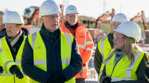 PA Media John Swinney wearing a yellow high-vis jacket and white hard hat with several similarly dressed members of the CIP team on the construction site at Coalburn 1 dqxikeidqkikdinv