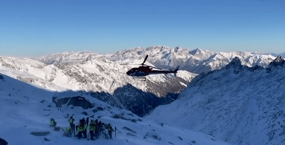 Helicopter over snowy mountains and rescue team. dqxikeidqkikdinv