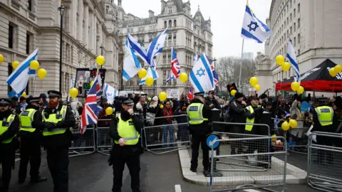 David Cliff/EPA-EFE/REX/Shutterstock Police at a protest rally with demonstrators waving flag of Israel dqxikeidqkikdinv