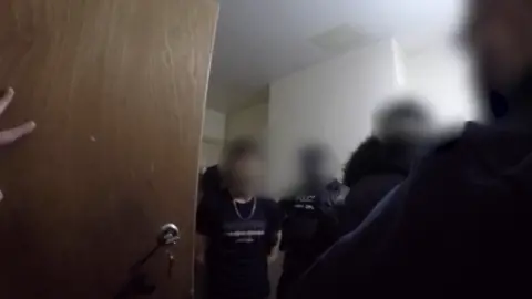 National Crime Agency Body worn footage of a man being arrested. He has several police officers around him and all faces are blurred dqxikeidqkikdinv