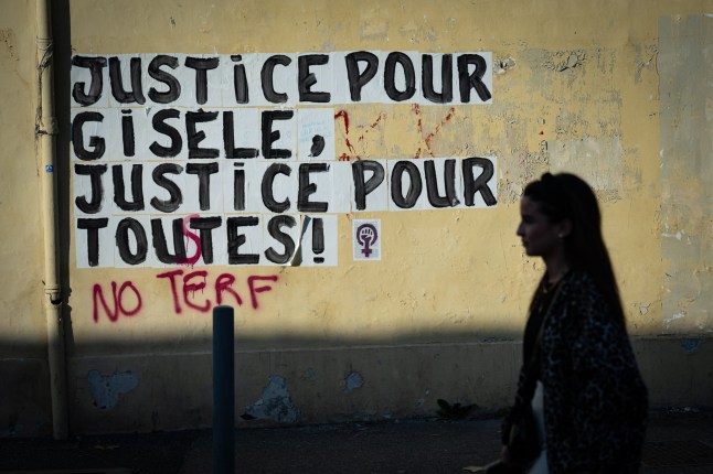 TOPSHOT - A pedestrian walks past a collage mural reading "Justice for Gisele, Justice for all" near the Avignon courthouse, where the Mazan rape trial takes place, in Avignon, southern France on December 18, 2024. Dominique Pelicot, 72, has been on trial since September for masterminding the mass rapes of his wife Gisele Pelicot by strangers who responded to his online invitation to visit the family home in Mazan, southern France. The verdict is expected on December 19, 2024 for Pelicot, who faces 20 years in jail after admitting the charges, and 50 other men are to be sentenced this week after a trial that has shocked France. (Photo by MIGUEL MEDINA / AFP) (Photo by MIGUEL MEDINA/AFP via Getty Images) dqxikeidqkikdinv