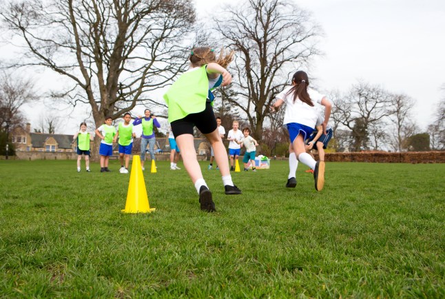 FDAA19 School children wearing sports uniform running around cones during a physical education session. dqxikeidqkikdinv