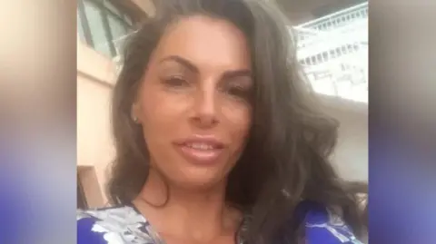 Supplied An image of Lisa Smith, who was killed in a fatal shooting outside the Three Horseshoes pub in Knockholt, Kent, on Friday. Lisa has long brown hair and is wearing a purple shirt with floral design, part of which is visible in the image. dqxikeidqkikdinv
