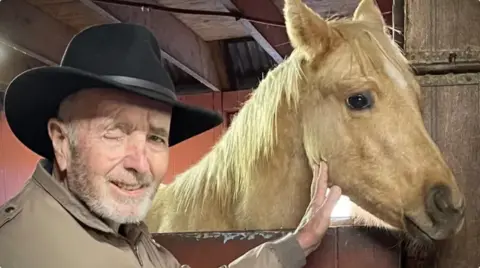 Lind Family/GoFundMe A man poses with a horse. The man is wearing a hat and missing his right eye. dqxikeidqkikdinv