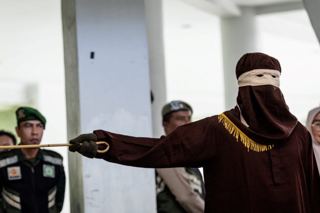 A member of the Sharia police flogs a man found guilty of sexual relations with another man under the strict Islamic sharia law, in Banda Aceh on February 27, 2025. (Photo by YASUYOSHI CHIBA / AFP) (Photo by YASUYOSHI CHIBA/AFP via Getty Images) dqxikeidqkikdinv