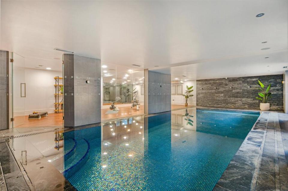 Indoor swimming pool with an adjacent gym visible through glass walls. dqxikeidqkikdinv
